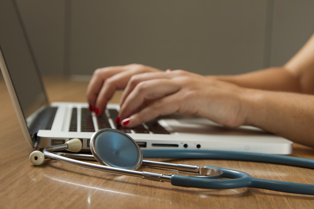 Hands typing on a laptop beside a stethoscope — website design and development for a Direct Primary Care practice